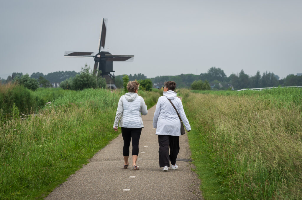 Whitney & Laura walking among the windmills at Werelderfgoed Kinderdijk
