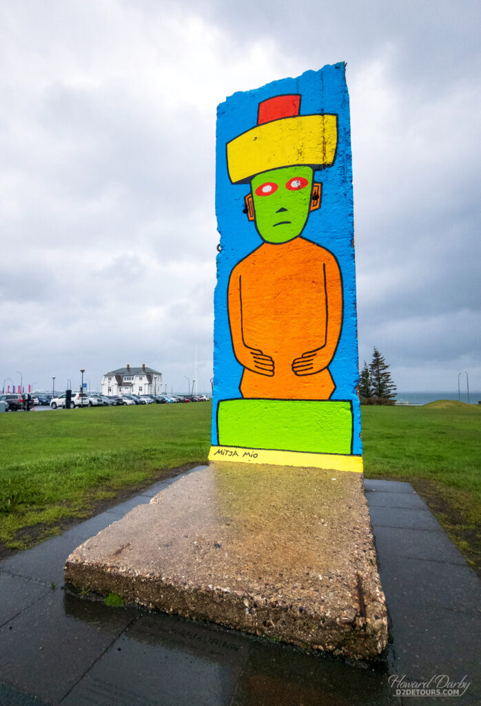 A painted chunk of the Berlin Wall stands near the Höfði House in the background - the piece of the wall was a gift to Reykjavík after The Reykjavik summit between Ronald Reagan and Mikhail Gorbachev that ended the Cold War was held in the Höfði House in 1986 