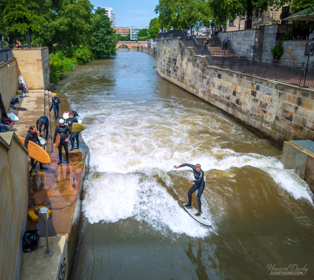 Urban surfers enjoying a wave built into the Leine river that winds through Hannover