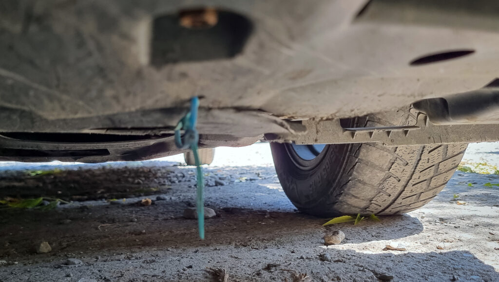 The lone zap-strap holding the cover under the engine in place... the rest was replaced by coat-hanger wire by a local mechanic we passed along the road