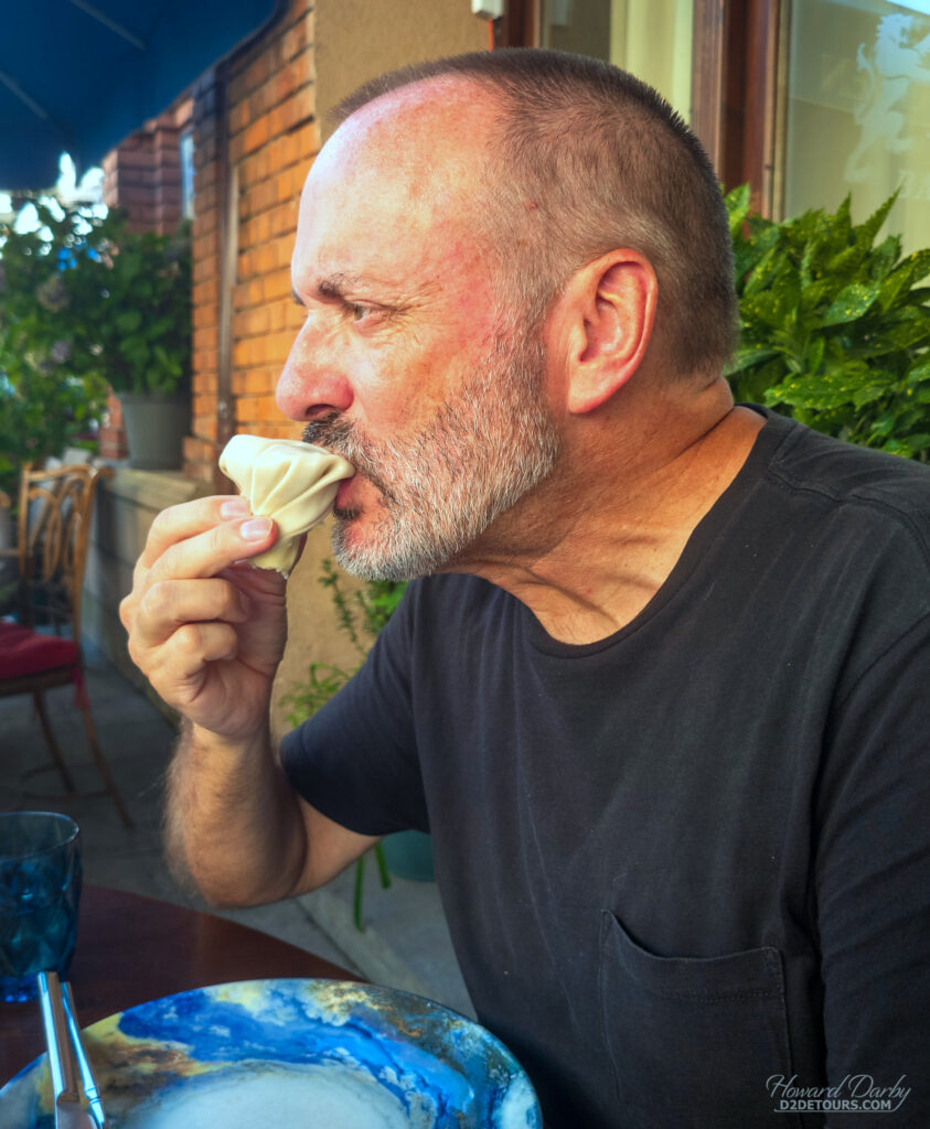 The proper way to eat a Khinkali ( I Googled it before trying): pick it up by the "kudi" tail, turn upside-down, bite a small hole in the top edge, then suck out the "soup" juices that are inside before eating the rest of the meat fille dumpling. The kudi dough lump is not eaten, and just left on the plate so you can count how many you consumed.